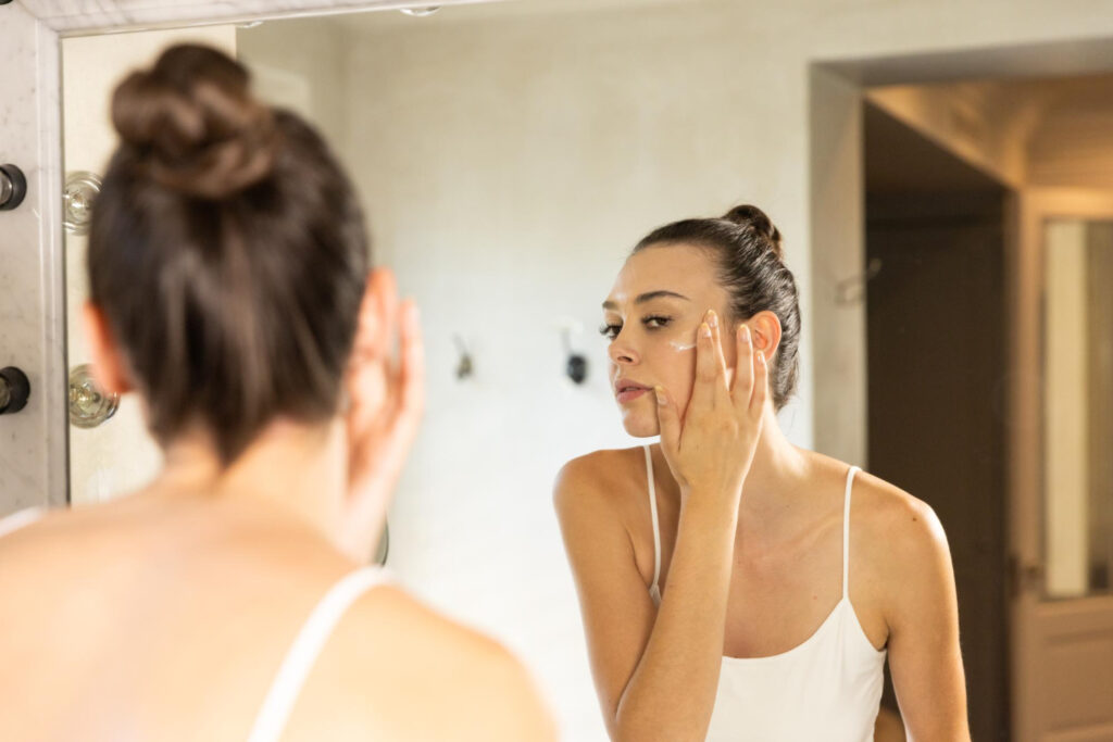 A woman applying cream on her face